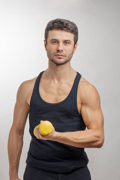 well-built handsome guy with yellow dumbbell - Foto, Imagem