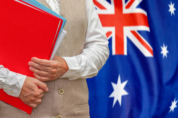 Avustralya bayraklı arka planda kırmızı klasörü olan bir kadın. Avustralya 'da eğitim ve hukuk kavramı - Fotoğraf, Görsel