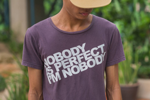 Młody człowiek w koszulce z napisem "Nikt nie jest doskonały, jestem nikim". - Zdjęcie, obraz