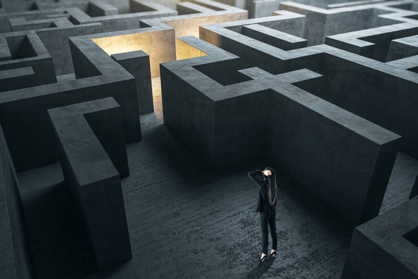 Young businesswoman in suit standing in concerete gray labyrinth. Business and challenge concept. - Photo, Image