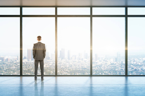 Young businessman standing in office hall with panoramic city view.  Job and occupation concept - Fotó, kép