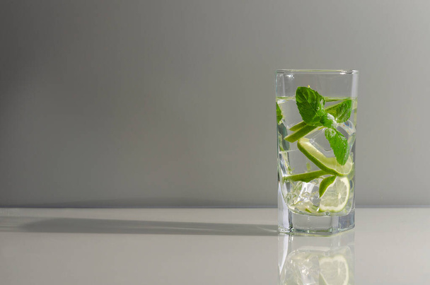 Mojito cocktail with lime and mint in tall glass. Fresh mojito in glass on a gray background. - Φωτογραφία, εικόνα