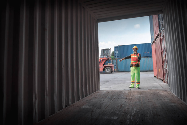 Ο επόπτης εμπορευματοκιβωτίων ελέγχει την εισαγωγή / εξαγωγή ενώ επιθεωρεί το κιβώτιο εμπορευματοκιβωτίων στη διανομή αποθηκών. Εμπορευματοκιβώτια Logistics Shipping Controlling της Βιομηχανίας Μεταφορών, Cargo Ship Factory - Φωτογραφία, εικόνα