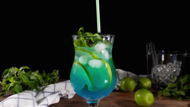 Woman putting straw into glass of tasty blue mojito cocktail on table - Footage, Video