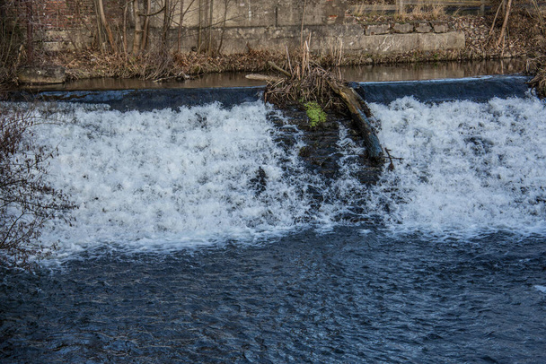 water uit een rivier schiet een stuw en schuim naar beneden - Foto, afbeelding