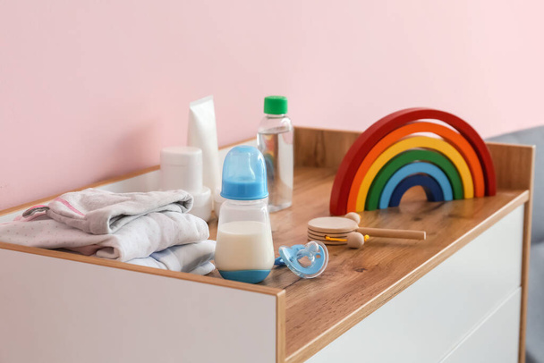 Garrafa de leite para bebê com brinquedos e acessórios no peito das gavetas no quarto - Foto, Imagem