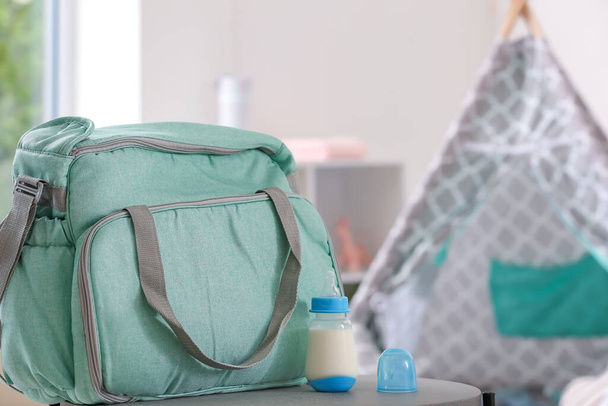 Bouteille de lait pour bébé avec sac sur la table dans la chambre - Photo, image