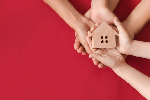 Hands of family with small house on color background - Photo, Image