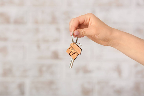 Female hand with key from house on light background - Foto, Imagem