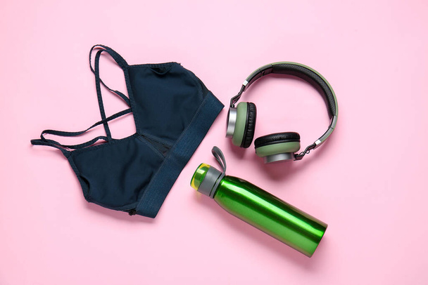 Ropa deportiva, botella de agua y auriculares sobre fondo de color - Foto, Imagen