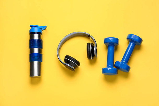 Dumbbells, bottle of water and headphones on color background - Photo, Image
