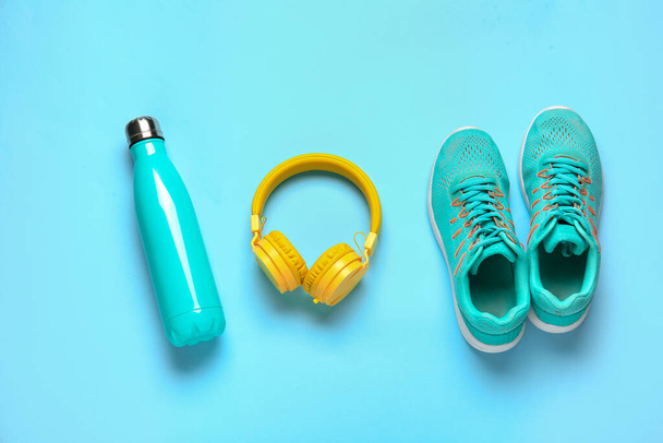Sportowe buty, butelka wody i słuchawki na tle koloru - Zdjęcie, obraz