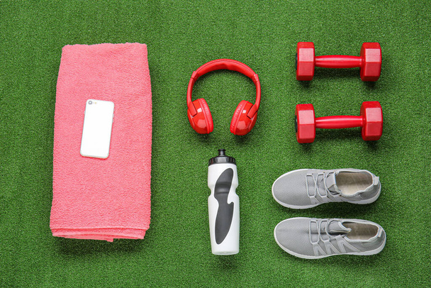 Sportieve schoenen, handdoek, halters, fles water, mobiele telefoon en koptelefoon op kleur achtergrond - Foto, afbeelding