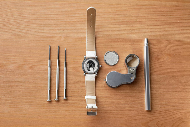 Reloj y herramientas para reparación sobre fondo de madera - Foto, Imagen
