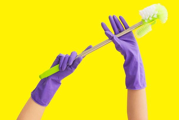 Mains dans les gants en caoutchouc tenant brosse de toilette sur fond de couleur - Photo, image