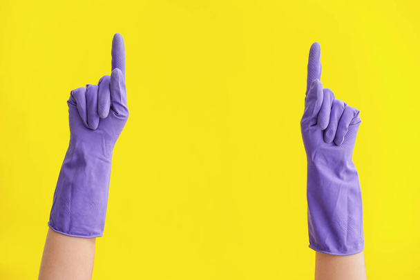 Hands in rubber gloves pointing at something on color background - Foto, afbeelding