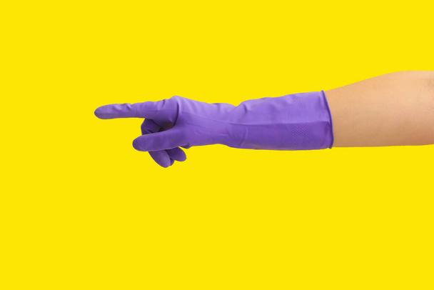 Guante de mano en goma apuntando a algo en el fondo de color - Foto, imagen