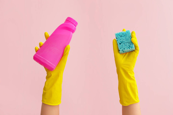 Hands in rubber gloves holding sponge and detergent on color background - Foto, immagini