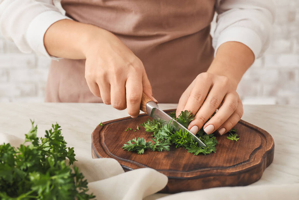 Woman cutting fresh parsley at table, closeup - Foto, afbeelding