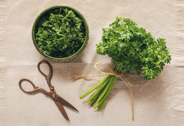 Bowl with fresh parsley and scissors on table - Foto, afbeelding