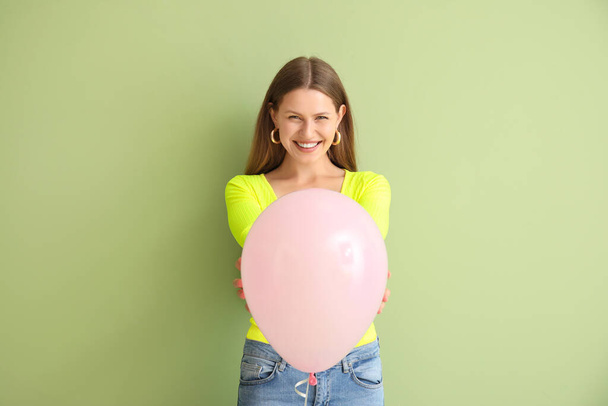 Young woman with balloon on color background - Foto, afbeelding