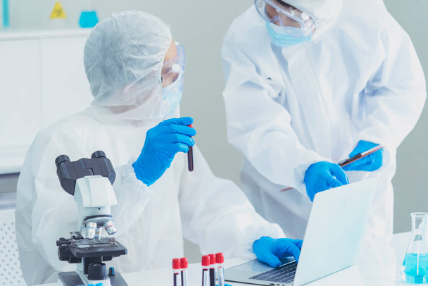 Két ázsiai tudós csapat rezerch kémia kémia kémcső kísérlet biotechnológiai antitest minta laboratóriumi kultivált vakcina ellen covid-19 vírus. Tudós konzultál, analizál a kémiai laboratóriumban - Fotó, kép