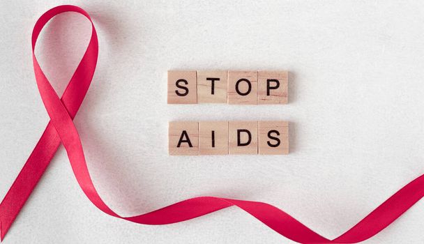 Konzept für den Welt-AIDS-Tag. Rotes Band in der Nähe von Holzbuchstaben. Baner, Kopierraum. AIDS stoppen - Foto, Bild
