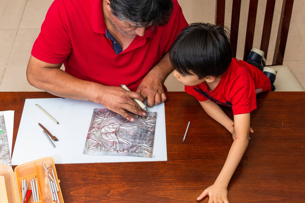 man teaching how to make an embossed frame to a young child - Photo, Image