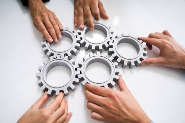Innovative Businesspeople Team Hands Joining Gears At Desk - 写真・画像