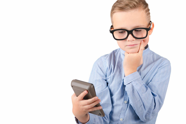Child holding calculator. Portrait of funny cute school boy thinking of something holds calculator looking at calculator. White isolated background. - Photo, Image