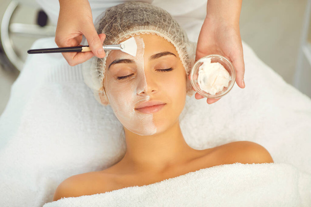 Dermatologist putting moisturizing mask to womans face during skincare procedure - Фото, зображення