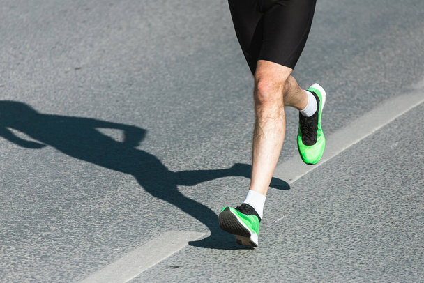 Laufsport. Mann läuft Beine und Schuhe in Aktion auf der Straße im Freien bei Sonnenuntergang. Männliches Athletenmodell - Foto, Bild