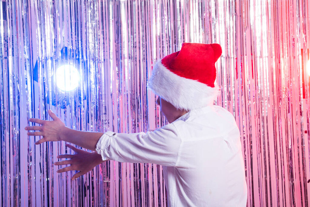 Aranyos vicces Santas segítő táncol fényes háttérrel. Karácsonyi ünnepek fogalma. - Fotó, kép