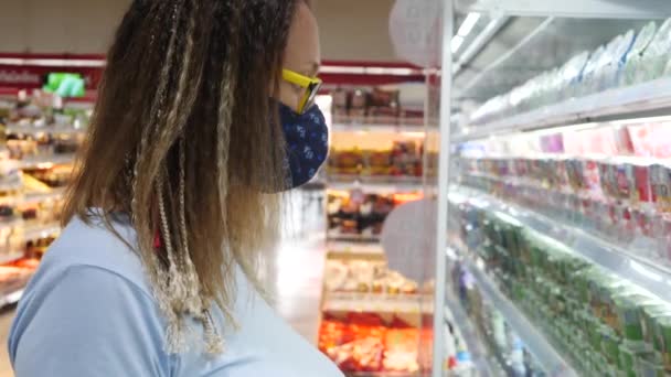 Mladý dospělý zákazník žena v ochranné masce obličeje na trhu - Záběry, video