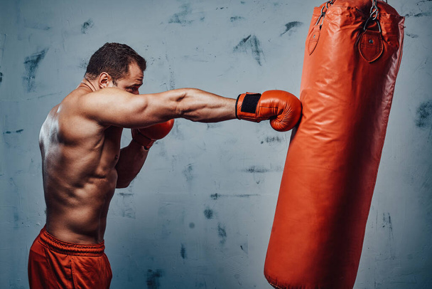 Boxer avec gants de protection frappant un sac de boxe - Photo, image