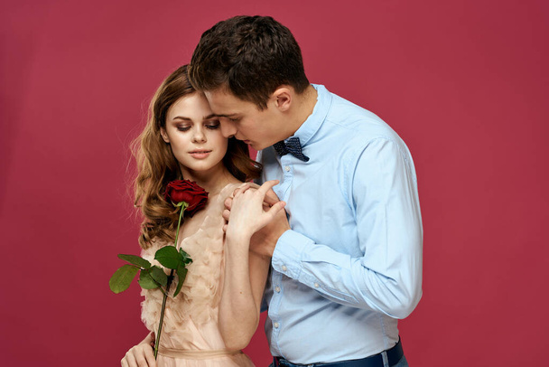 Gli amanti persone con rosa in mano su sfondo rosa isolato abbracciare emozioni felicità romanticismo sentimenti - Foto, immagini