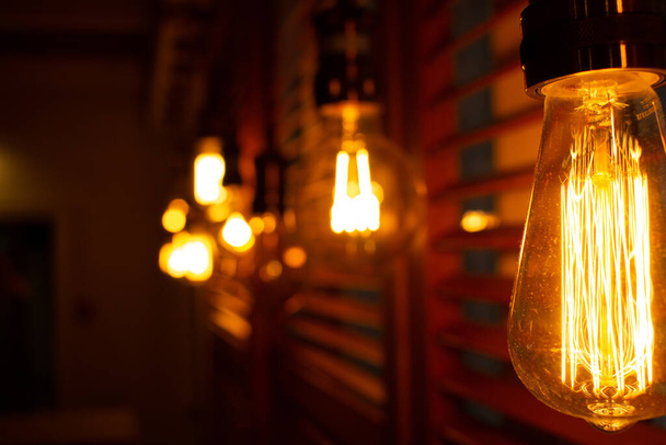 Zlaté zářící starožitné žárovky Edisonova stylu ve tmě. Koncept osvětlení výzdoby. Staré žárovky. Rozmazat pozadí retro světel - Fotografie, Obrázek