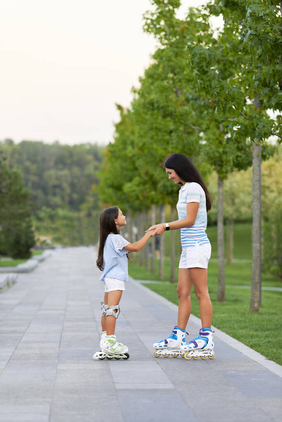 mother and her little daughter rollerskating - Photo, image