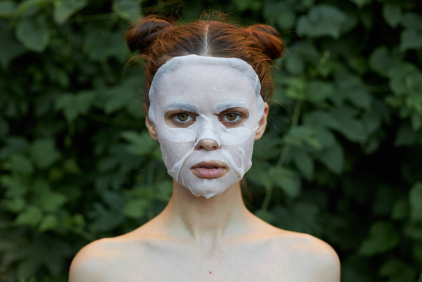 Nice woman Anti-wrinkle mask bare shoulders bushes in the background - Foto, imagen