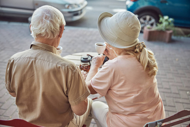 Aged married Caucasian couple drinking tea outdoors - Фото, изображение