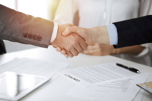 Business people shaking hands finishing contract signing in sunny office, close-up. Handshake and marketing - Foto, imagen