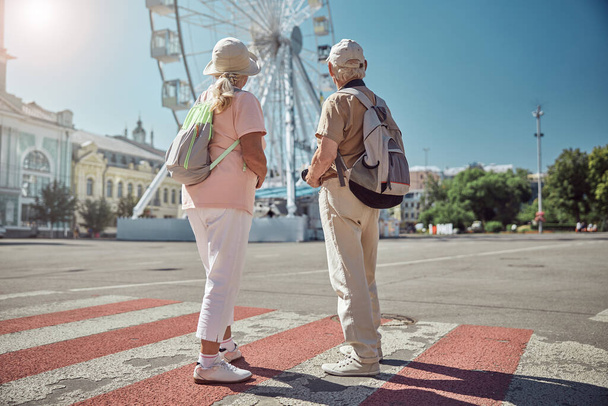 Tourist couple standing at the pedestrian crossing - Zdjęcie, obraz