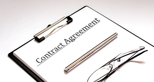 Pen, bril op het contract papieren op witte achtergrond - Foto, afbeelding