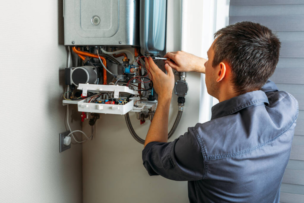 Plumber attaches Trying To Fix the Problem with the Residential Heating Equipment. Repair of a gas boiler - Foto, Imagen