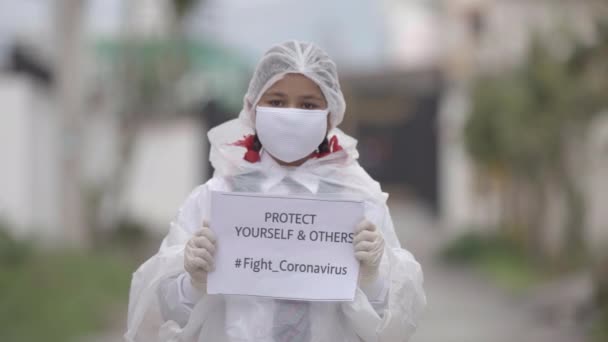 COVID-19 Coronavirus - Dodelijk virus: Meisje met masker, handschoenen en beschermende jurk in schooluniform voor de veiligheid tegen COVID-19 Coronavirus. Apple ProRes 422.Meisje verspreidt bewustzijn - Video