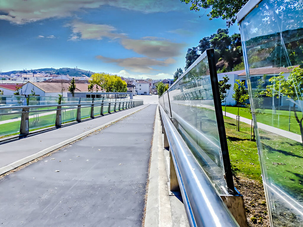 View with a sidewalk with glass railings from a city park - Photo, Image