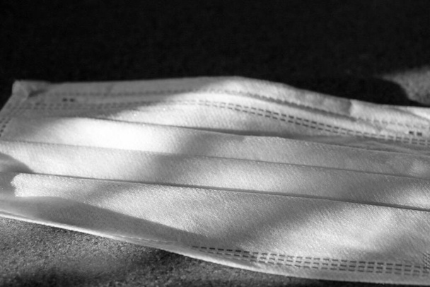 Some light falls on the medical mask. Black and white photo. Coronavirus protection - Photo, Image