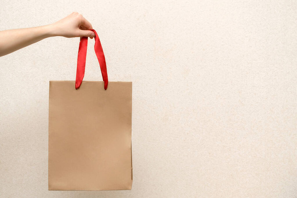 woman holding craft shopping bag. Close up female holds in hand brown empty paper blank package for takeaway isolated on background. Delivery courier service concept mock up with copy space - Zdjęcie, obraz