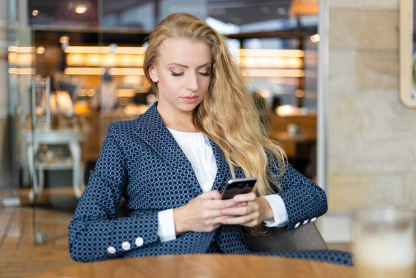Young businesswoman using her smartphone to browse web content and sending messages - Photo, image