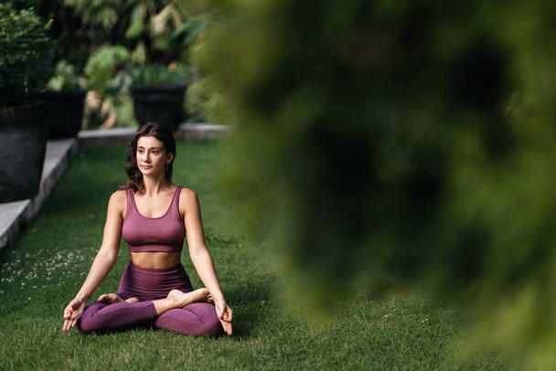 Woman practicing yoga performing yoga-asanas outdoors. - Фото, изображение